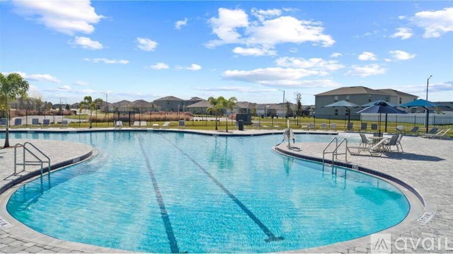 A large outdoor swimming pool with a sunny sky in the background.
