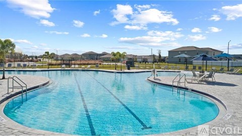 A large outdoor swimming pool with a sunny sky in the background.