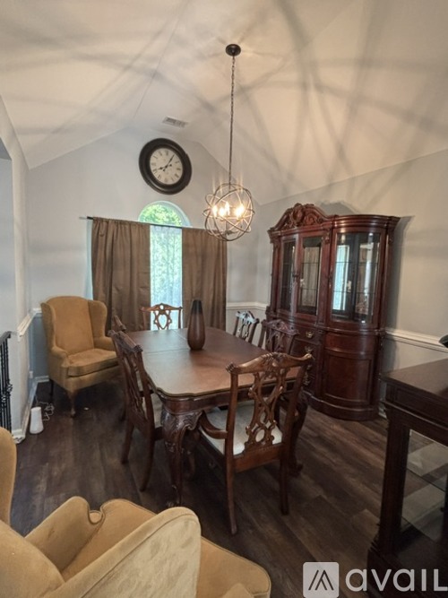 A dining room with a table set for four and a chandelier hanging from the ceiling.