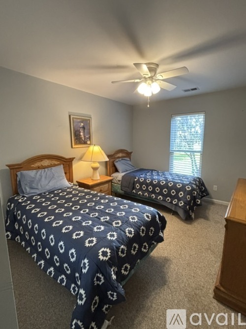 A bedroom with two beds and a ceiling fan.
