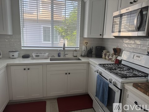 A kitchen with white cabinets and a stove top oven.