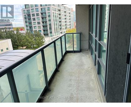 A balcony with glass railings and a view of a cityscape.