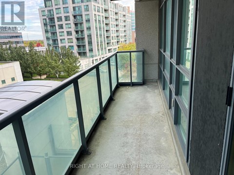 A balcony with glass railings and a view of a cityscape.