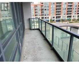 A balcony with glass railings and a view of a building across the way.