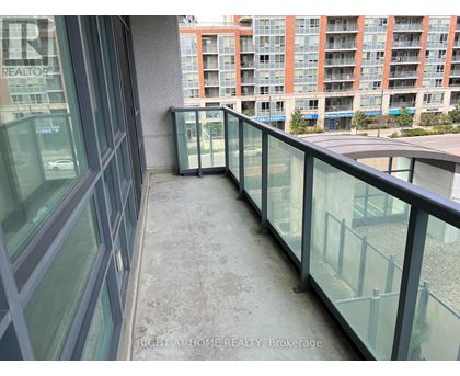 A balcony with glass railings and a view of a building across the way.