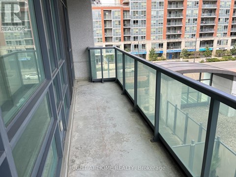 A balcony with glass railings and a view of a building across the way.