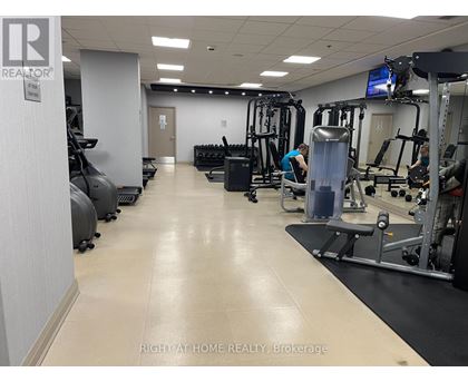 A gym with a variety of equipment and two people working out.