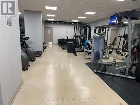 A gym with a variety of equipment and two people working out.