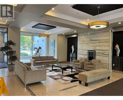 A well-lit living room with a large couch, a coffee table, and a fireplace.