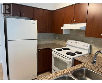 A kitchen with a white fridge, white stove and brown cabinets.