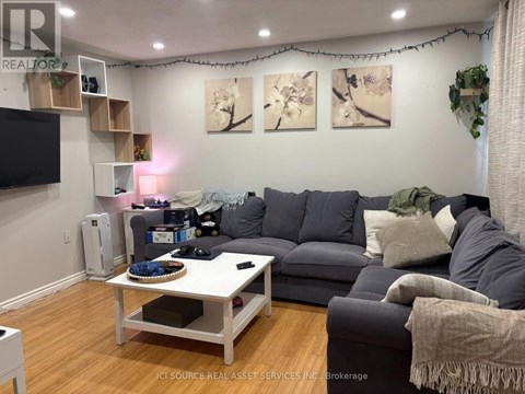 A living room with a grey couch, a white coffee table, and a TV on the wall.