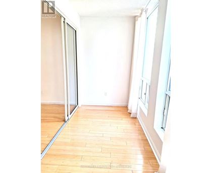 A room with a sliding glass door and wooden flooring.