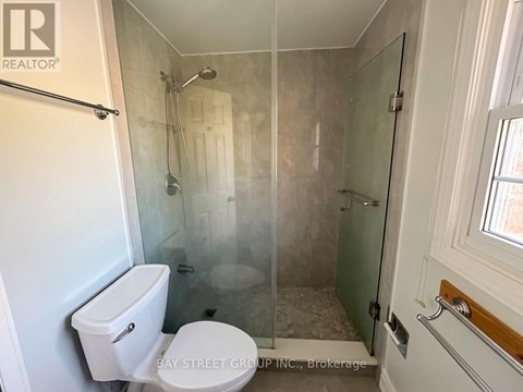 A white toilet sits in a small bathroom with a glass shower door.
