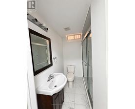 A white bathroom with a toilet, sink and mirror.