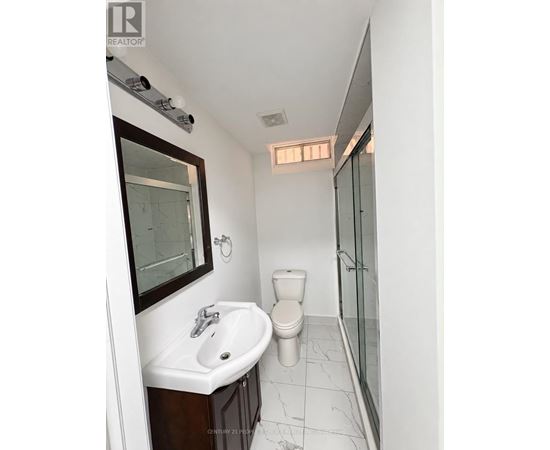 A white bathroom with a toilet, sink and mirror.