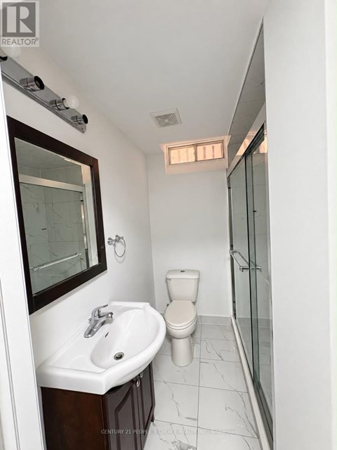 A white bathroom with a toilet, sink and mirror.