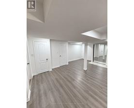 A spacious room with wood flooring and white walls.