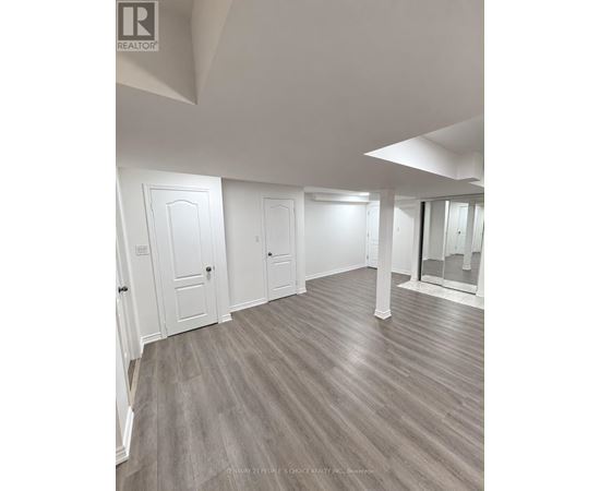 A spacious room with wood flooring and white walls.