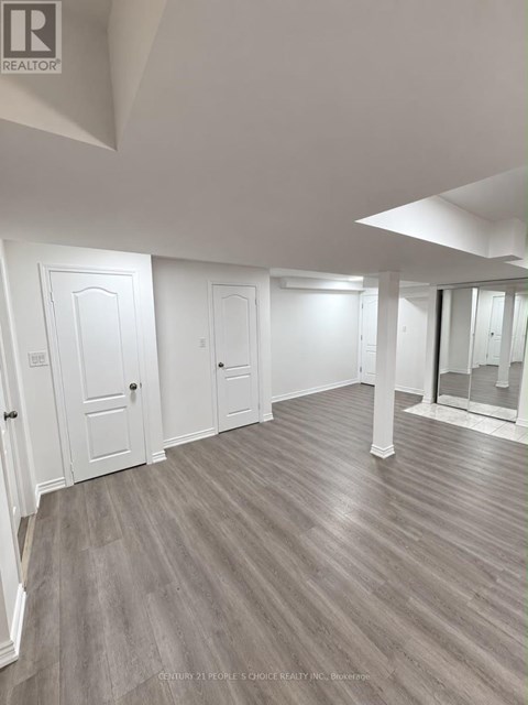 A spacious room with wood flooring and white walls.