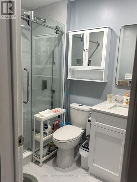 A white toilet with a white cabinet and a glass shower stall.