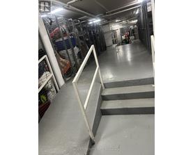 A long hallway with a metal railing on the left and a staircase on the right.