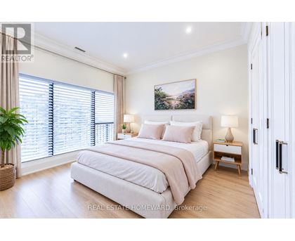 A bedroom with a large bed, a potted plant, and a painting on the wall.