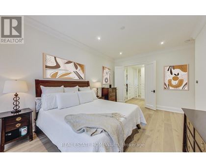 A bedroom with a large bed and a painting on the wall.