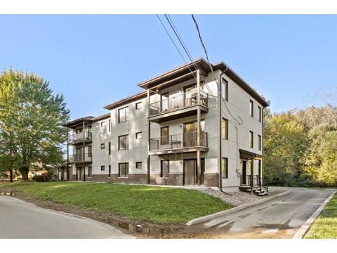 A modern apartment building with a balcony on the second floor.