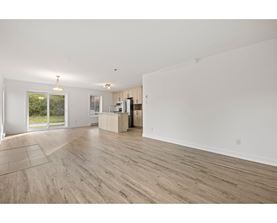A spacious room with wooden flooring and white walls.