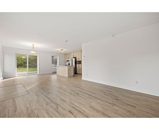 A spacious room with wooden flooring and white walls.