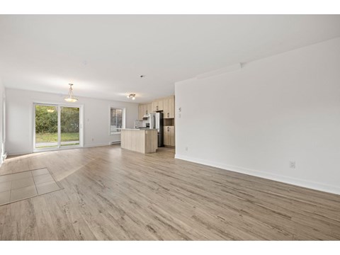 A spacious room with wooden flooring and white walls.