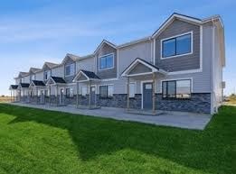 A row of houses with a green lawn in front.