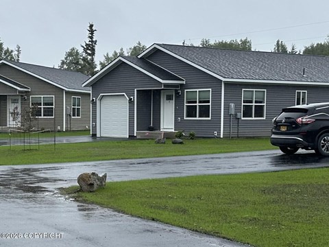 A grey house with a black car parked in front.