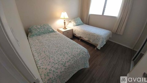 A bedroom with two beds and a nightstand with a lamp.