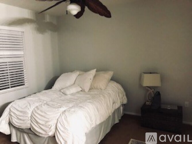 A bedroom with a bed, nightstand, and window with blinds.