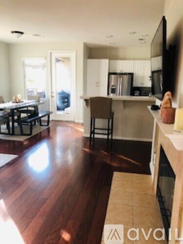 A kitchen with a wooden floor and a dining table with chairs.