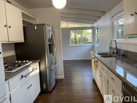A kitchen with a black refrigerator and white cabinets.