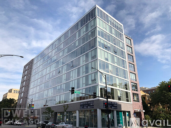 A modern glass building stands tall on a street corner.