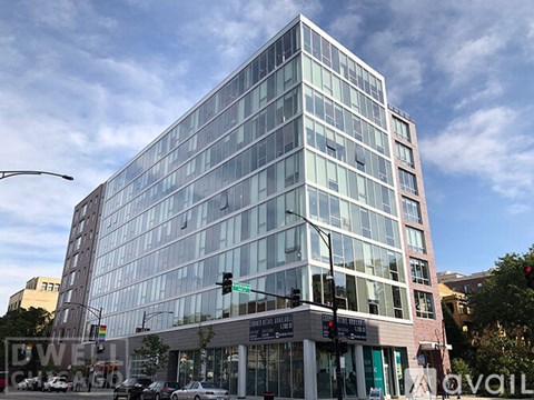 A modern glass building stands tall on a street corner.