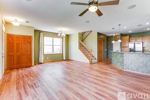 A spacious room with wooden floors and a staircase.