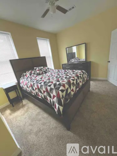 A bedroom with a bed, dresser, and mirror.