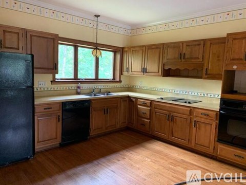 A kitchen with wooden cabinets and a black refrigerator.
