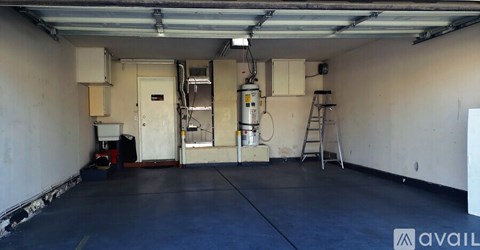A spacious garage with a ladder and a white cabinet.