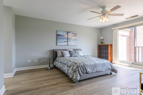 A bedroom with a bed, a ceiling fan, and a painting on the wall.