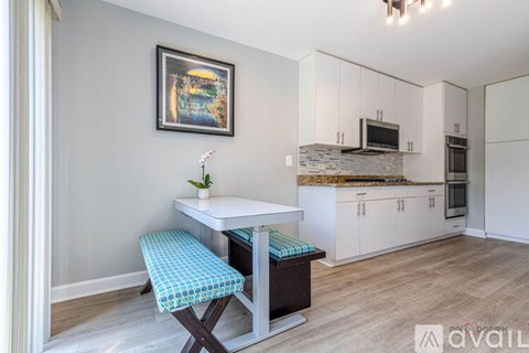 A kitchen with a table and a bench with a painting on the wall.