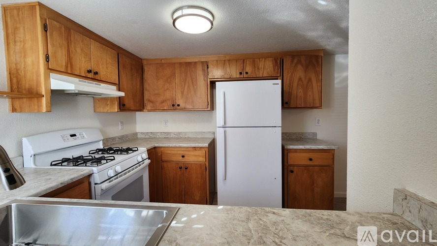 A kitchen with wooden cabinets and a white fridge.