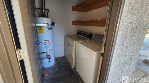 A small, white dishwasher is in a narrow space between a wall and a door.