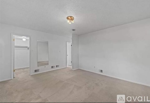 A spacious, empty room with a carpeted floor and white walls.