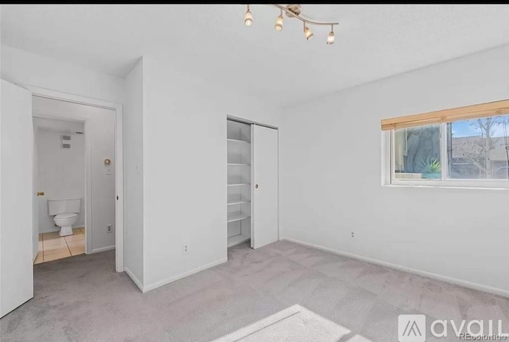 A room with a toilet, a sink, and a window.