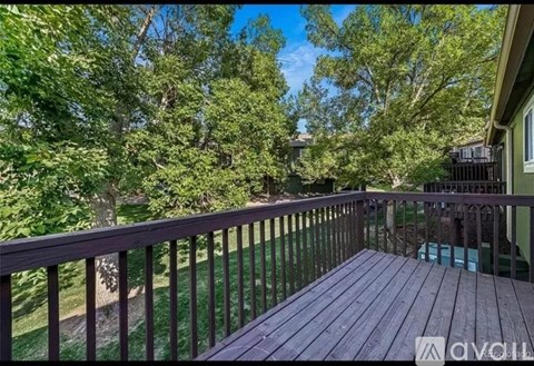A deck with a railing overlooking a green lawn and trees.